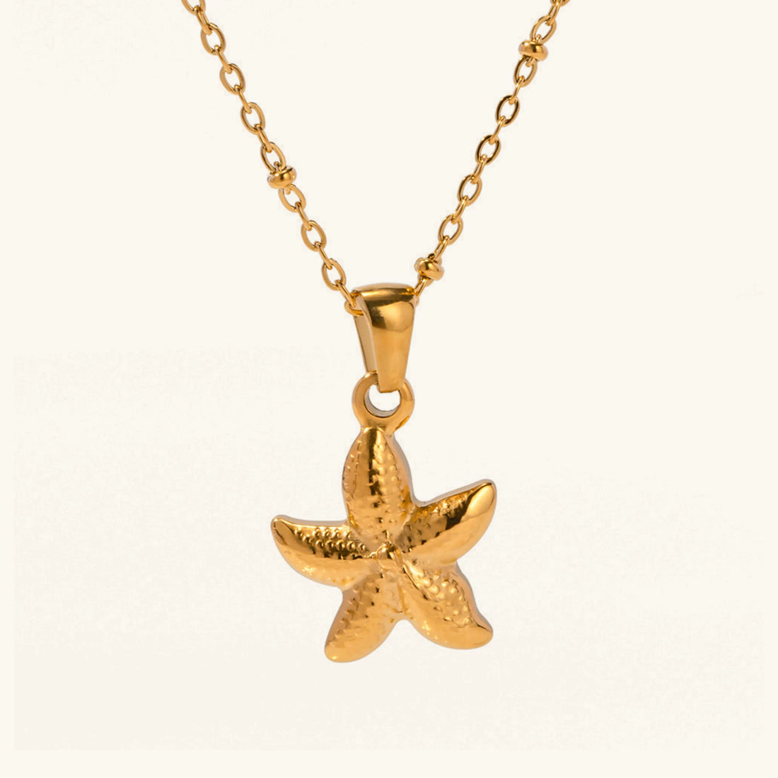 Gold starfish pendant on a chain against a white background