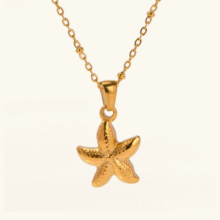Gold starfish pendant on a chain against a white background