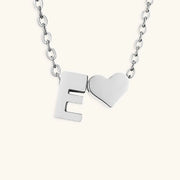 Silver necklace with letter 'E' and heart pendant on a white background