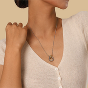 Woman wearing a delicate necklace with a small pendant on a beige background