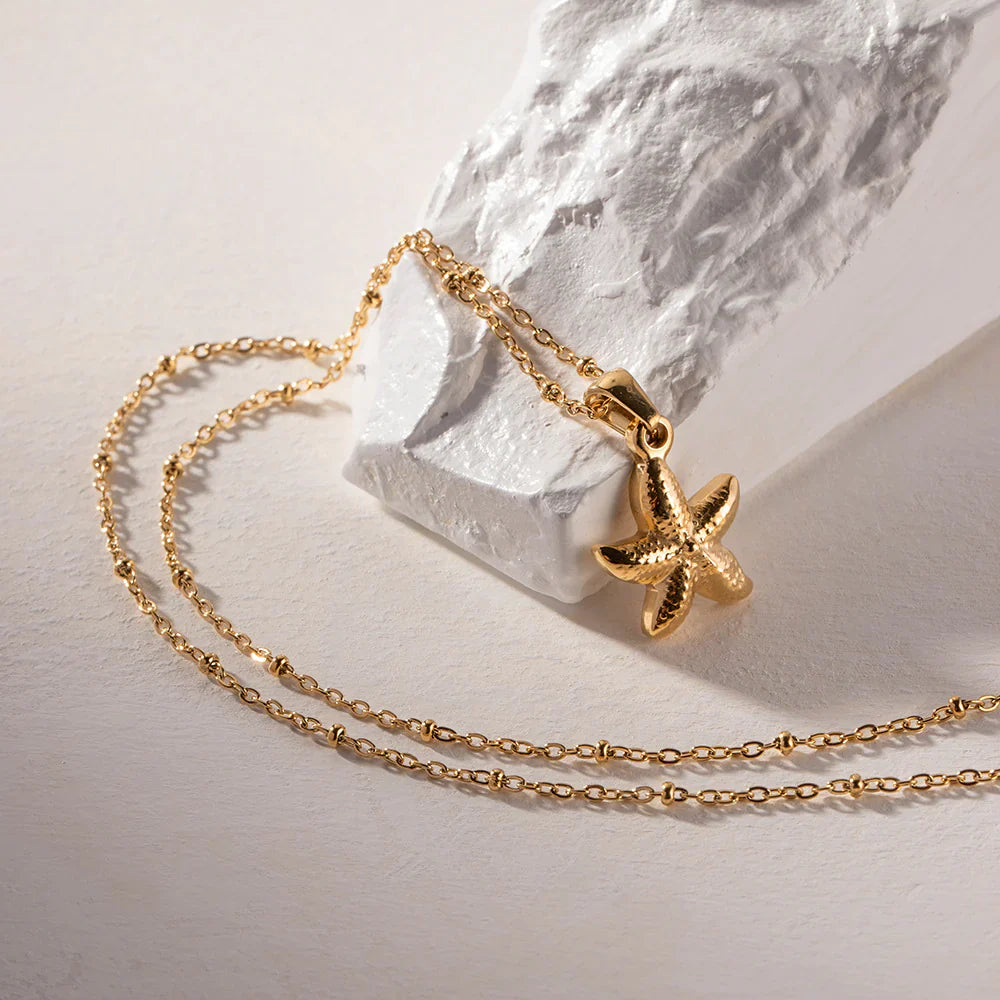 Gold necklace with a starfish pendant on a light background