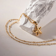 Gold necklace with a starfish pendant on a light background