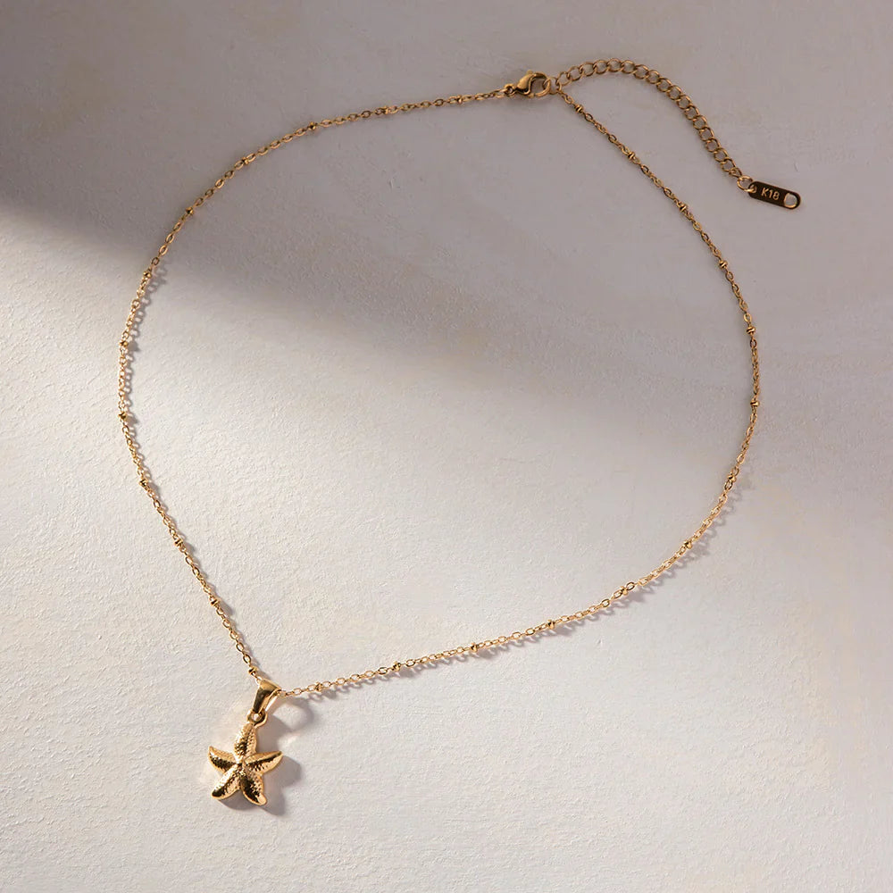 Gold necklace with a starfish pendant on a light background