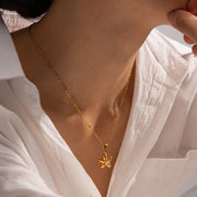 Gold necklace with a starfish pendant worn by a person in a white shirt.