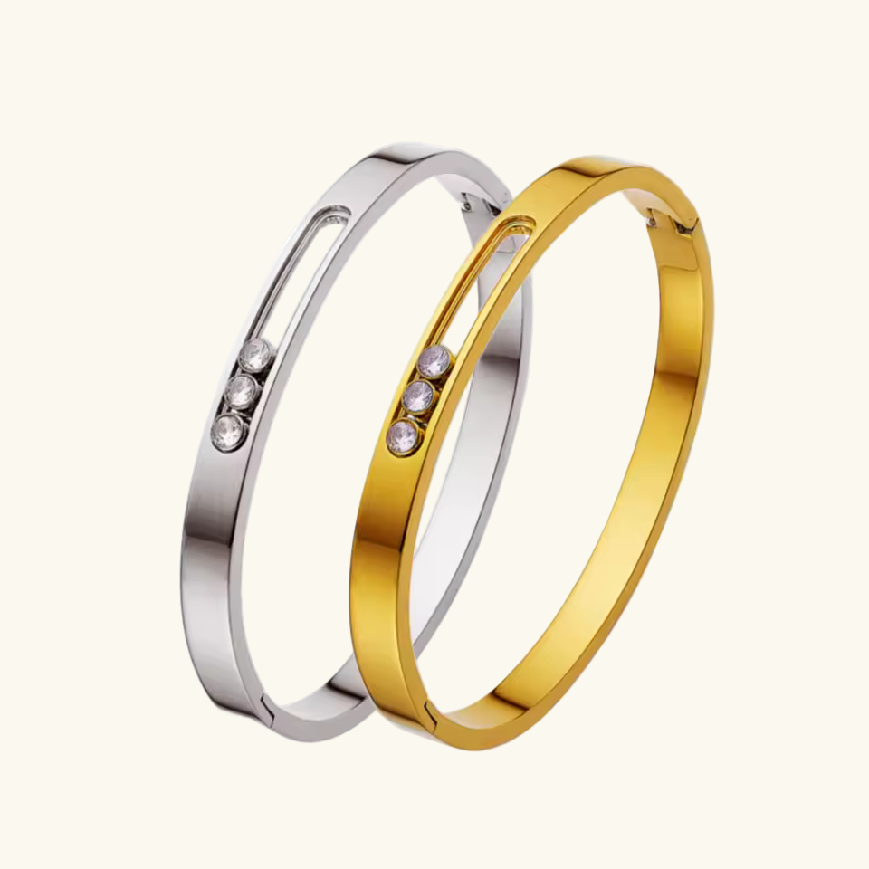 Two bracelets, one gold and one silver, with small stones on a white background