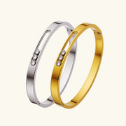 Two bracelets, one gold and one silver, with small stones on a white background