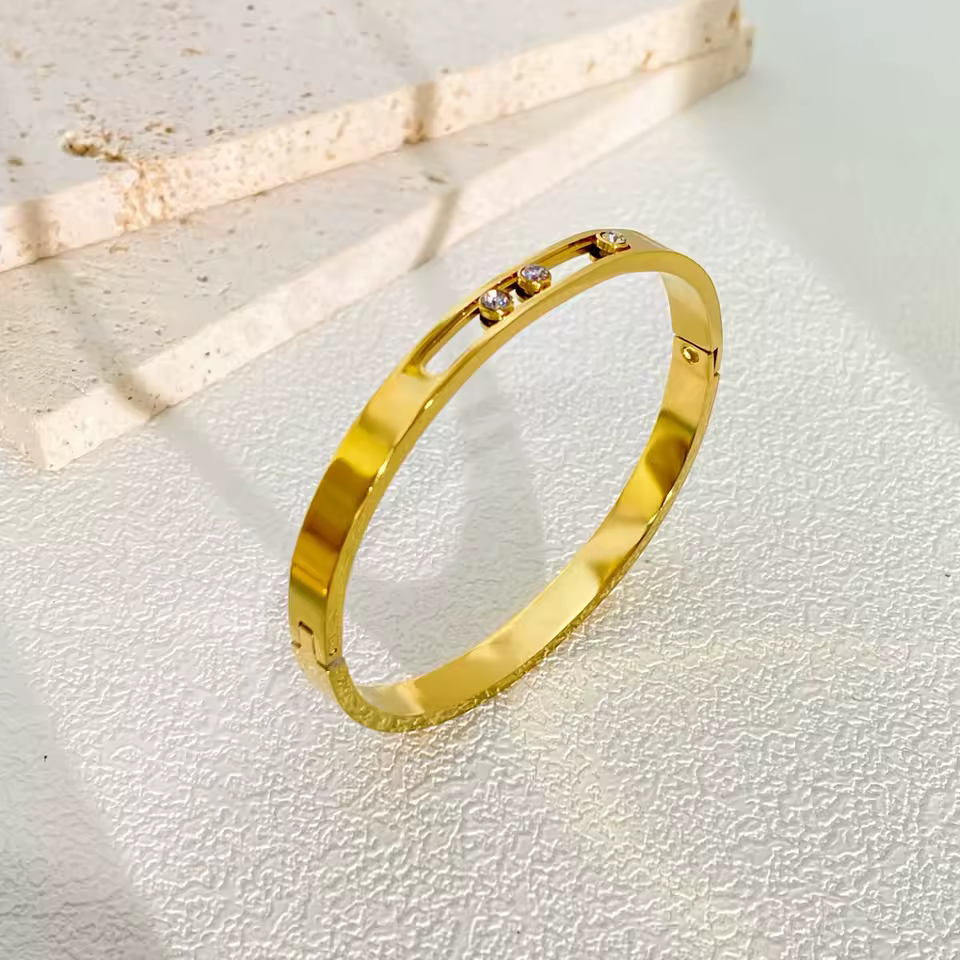 Gold bracelet with small diamonds on a textured white surface