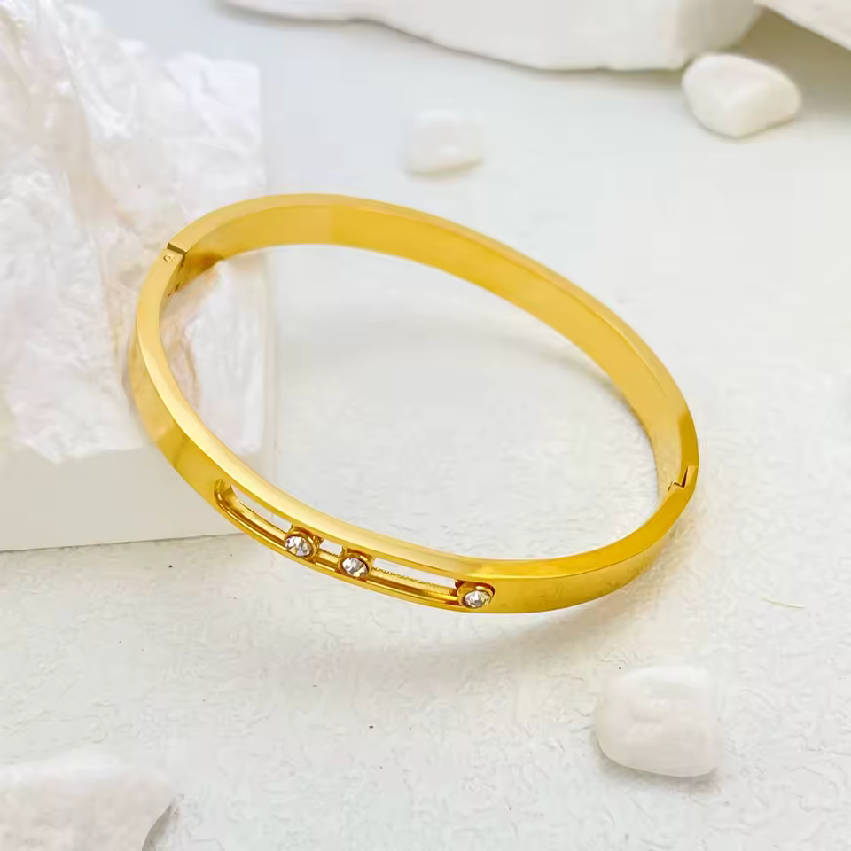Gold bracelet with small stones on a light background